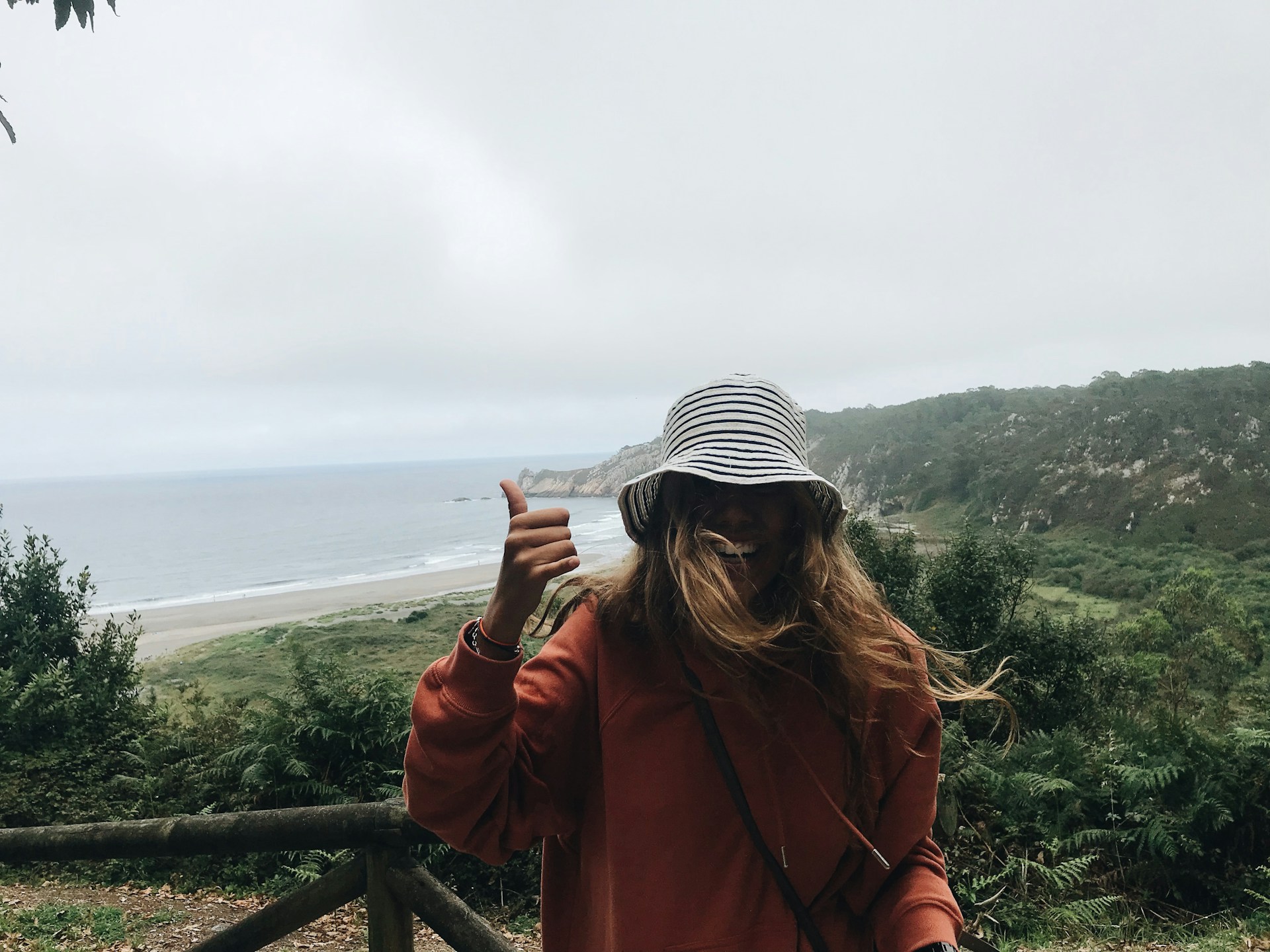 woman in black and white striped knit cap and red jacket standing on top of mountain
