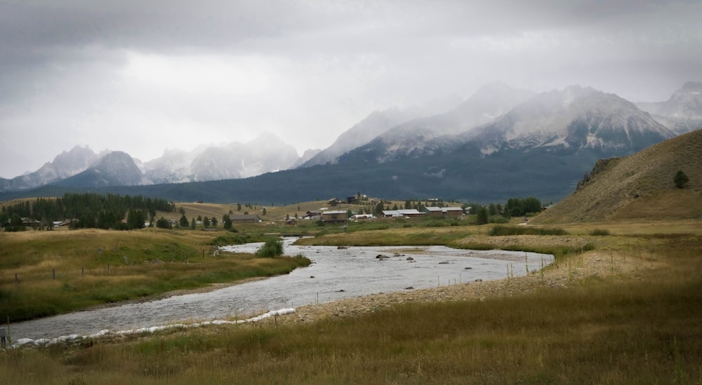 green grass field near lake under white clouds during daytime