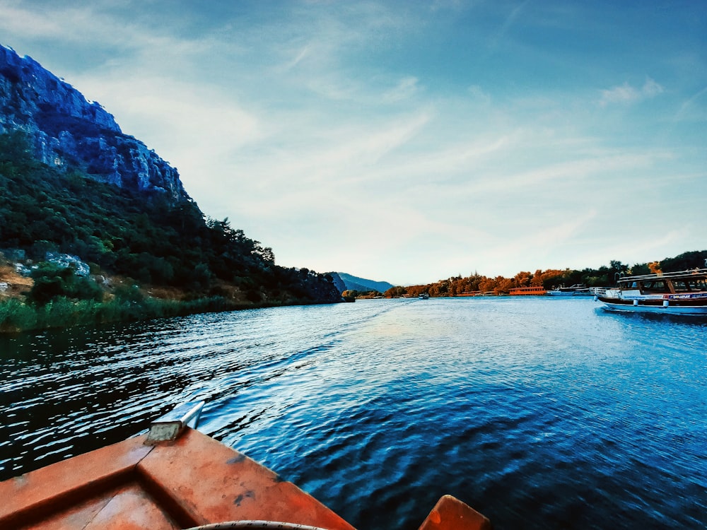 brown canoe on body of water near green mountain during daytime