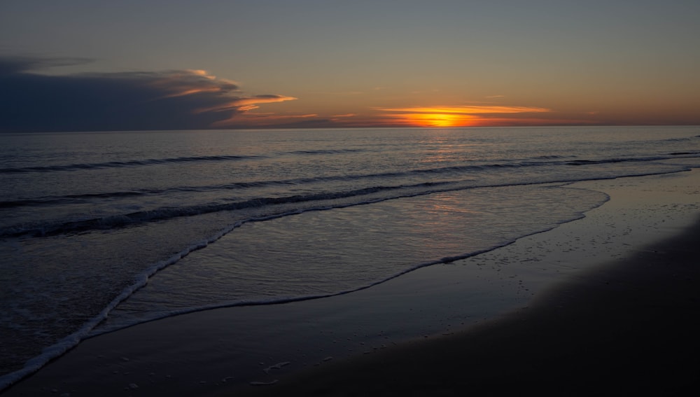 ocean waves crashing on shore during sunset