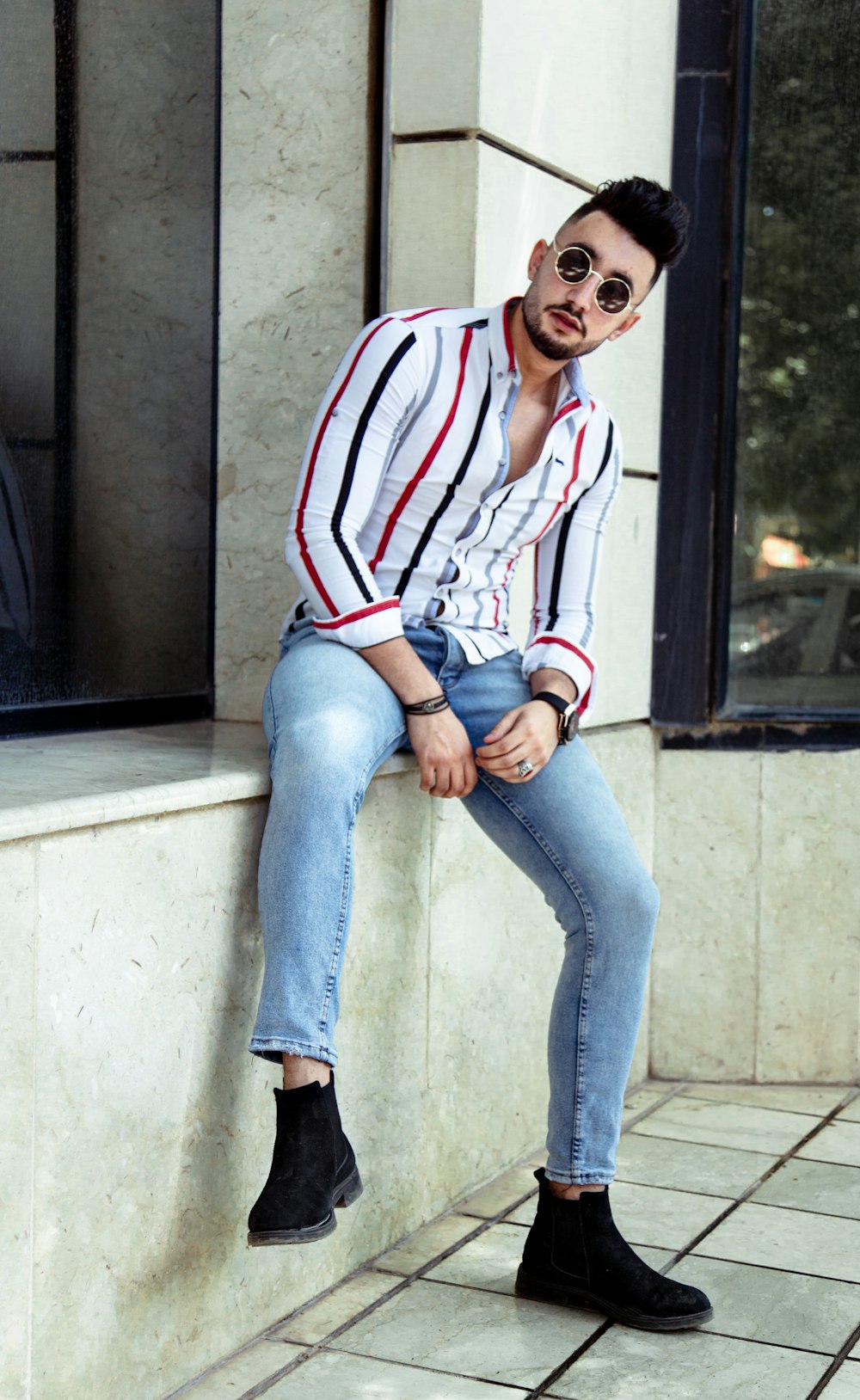 man in red white and blue striped long sleeve shirt and blue denim jeans sitting on on on on on