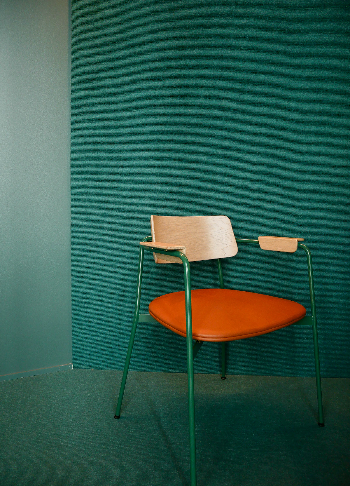 An orange chair against a green wall