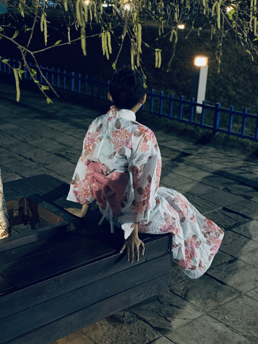 woman in white and pink floral kimono sitting on bench