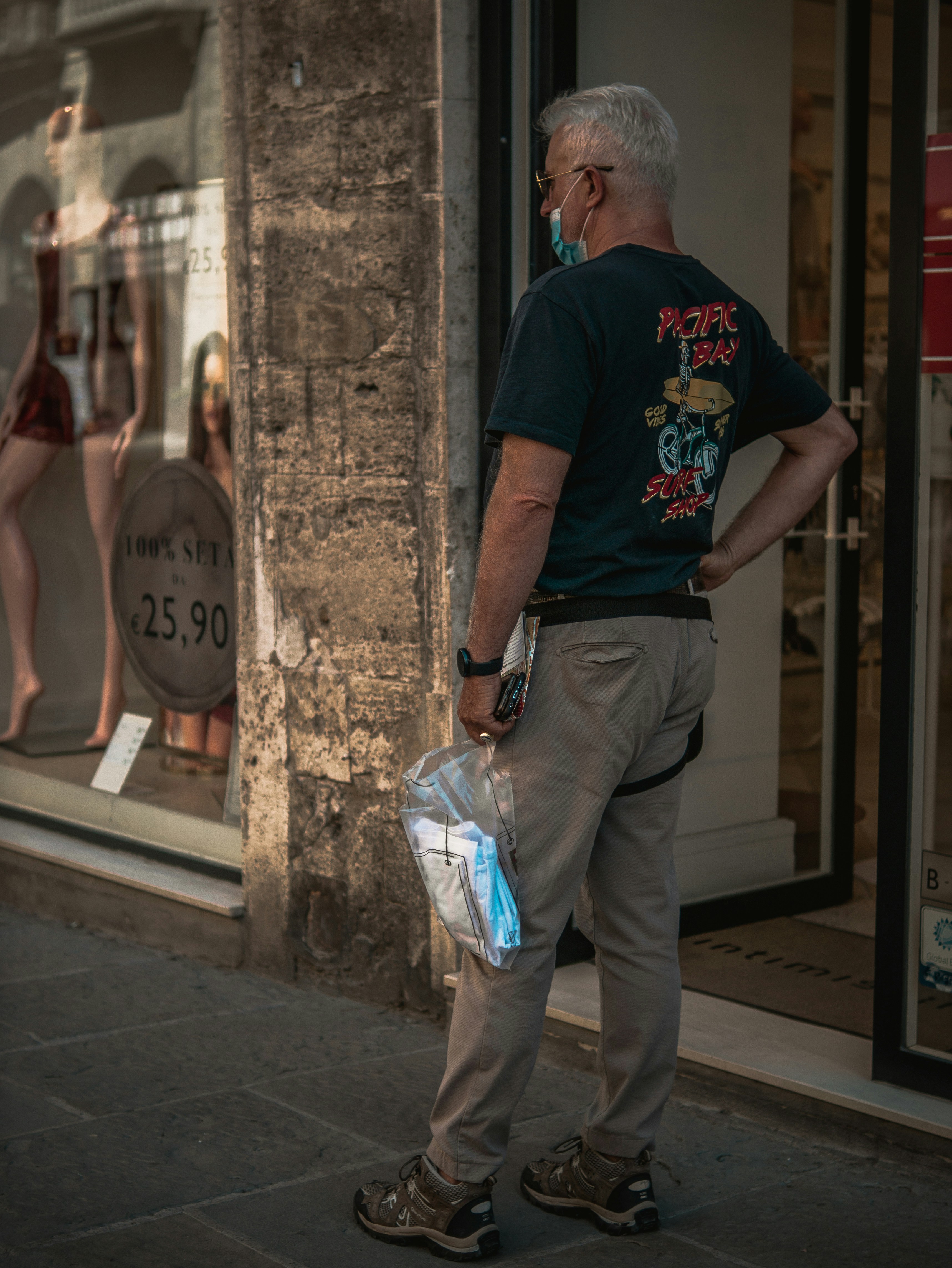 man in black crew neck t-shirt and gray pants holding white plastic bag