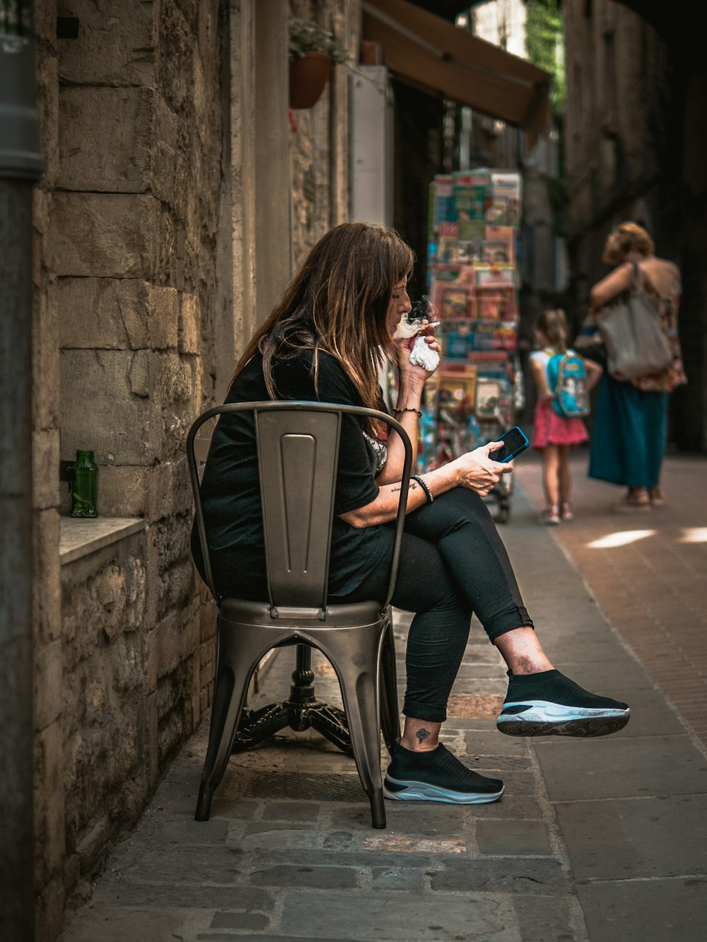 a woman sitting on a chair on a sidewalk