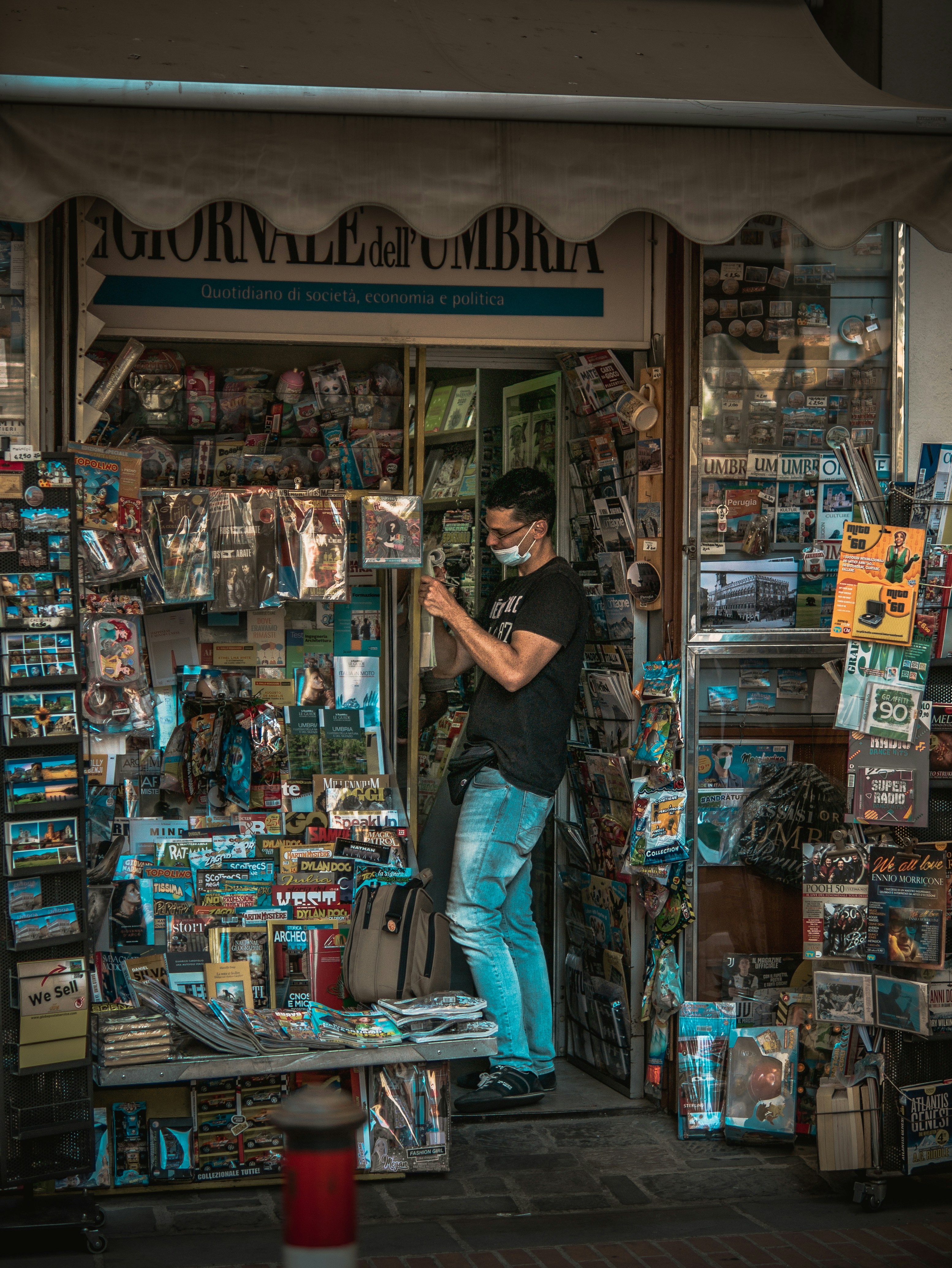man in black t-shirt and blue denim jeans standing in front of store