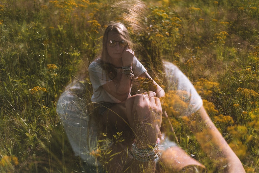 woman in brown coat sitting on green grass field during daytime