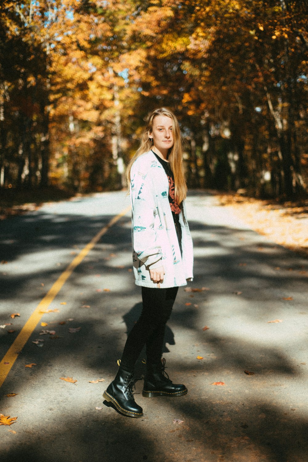 woman in white long sleeve shirt and black pants standing on gray asphalt road during daytime