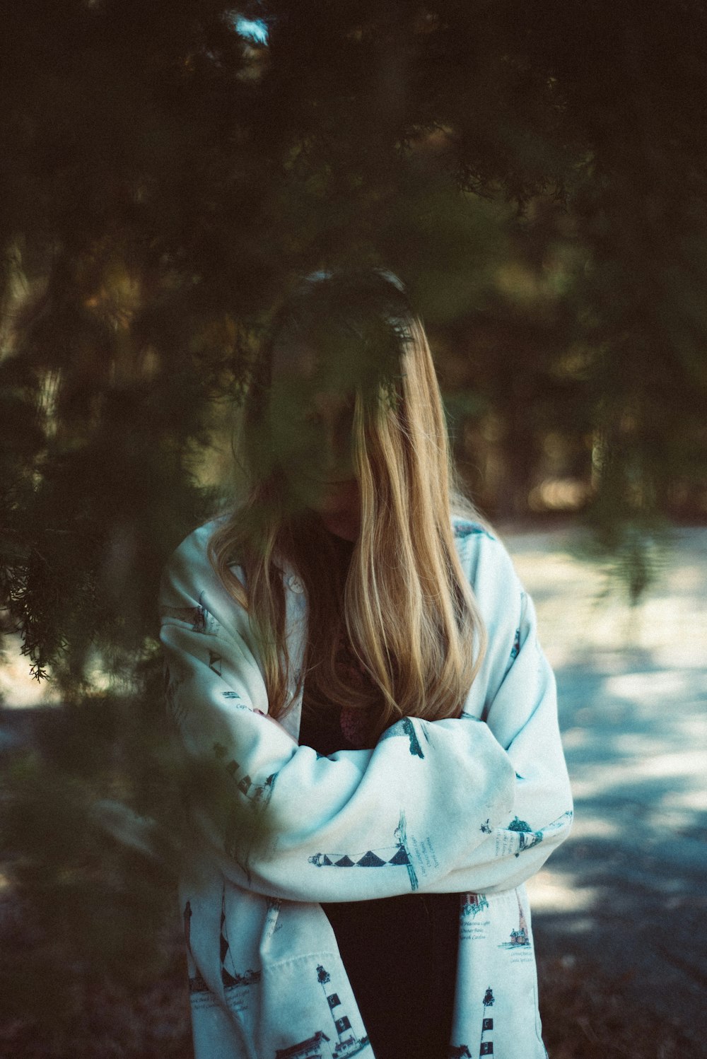 woman in white jacket standing near trees during daytime