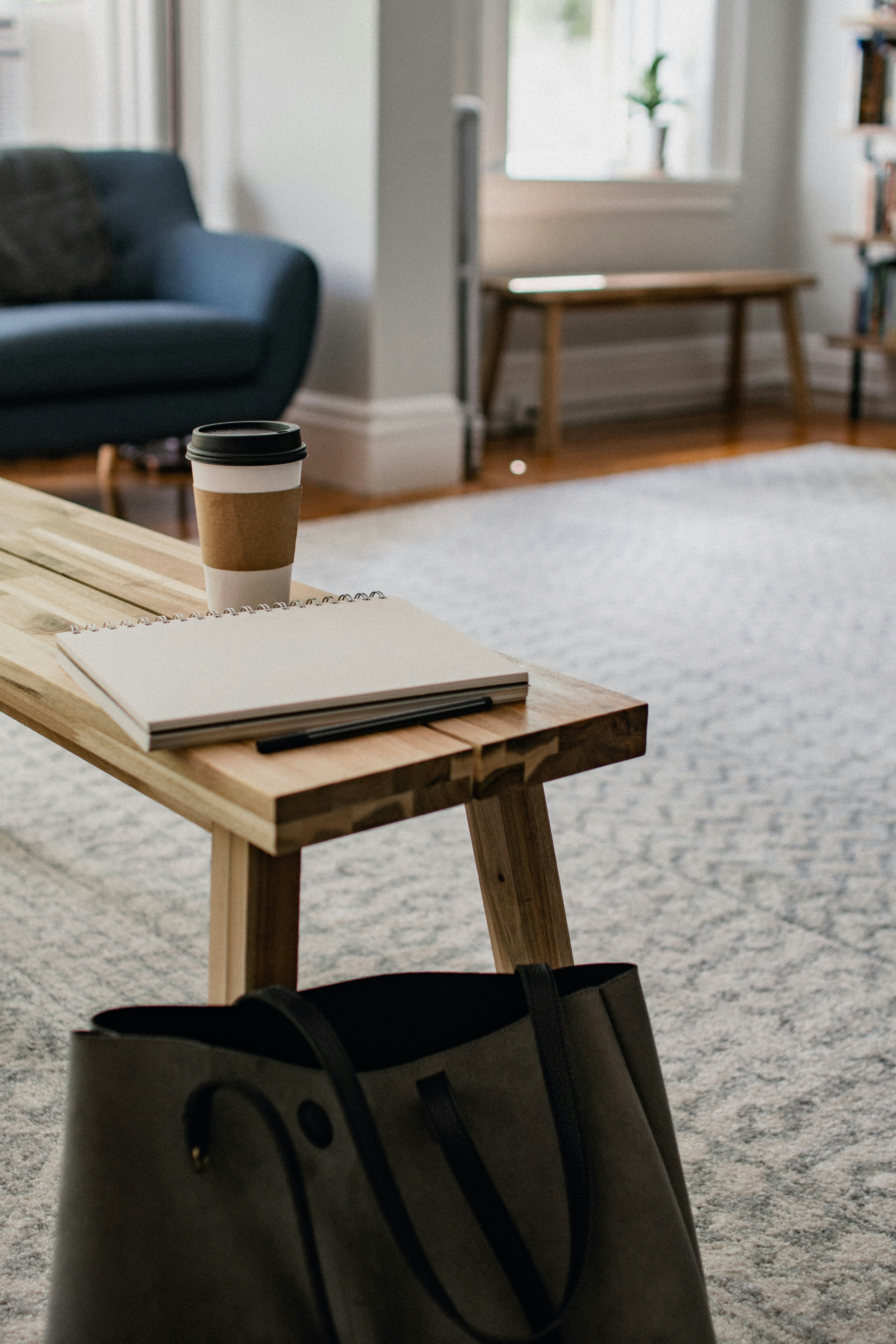 Notebook and purse on a wooden bench with notebook and coffee