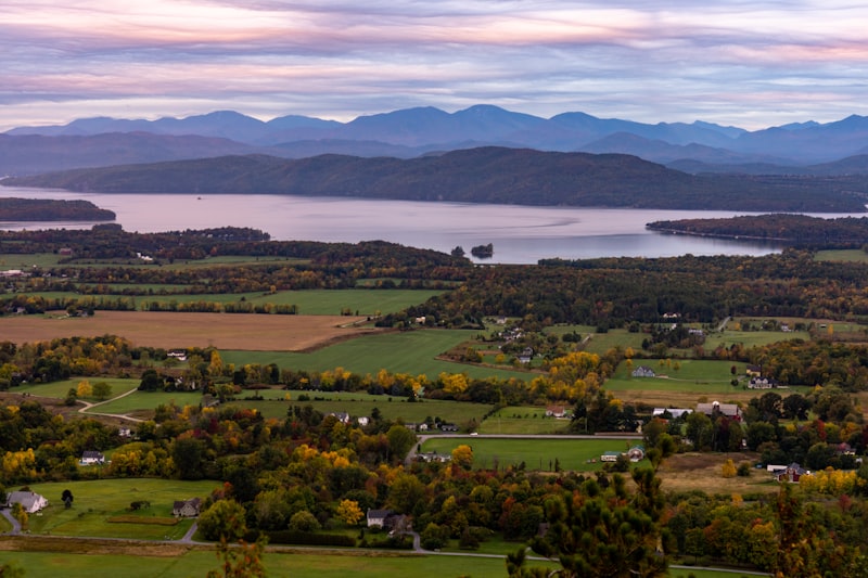 Vermont farmland and lake with autumn foliage and mountains at sunset