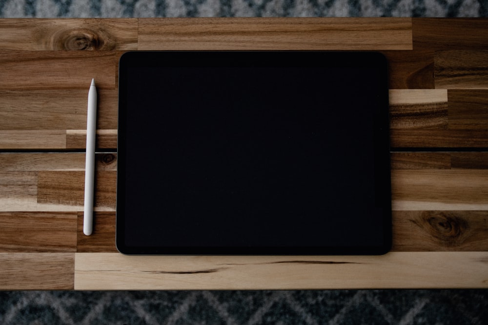 black ipad on brown wooden table