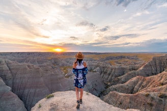 woman in black and white plaid dress standing on rocky hill during daytime