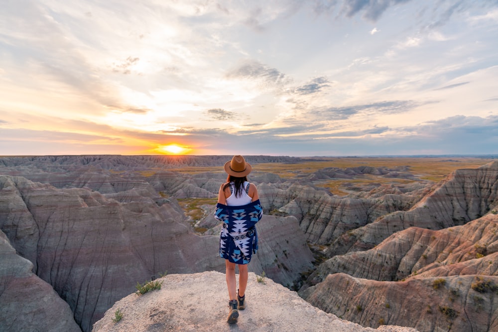 woman in black and white plaid dress standing on rocky hill during daytime