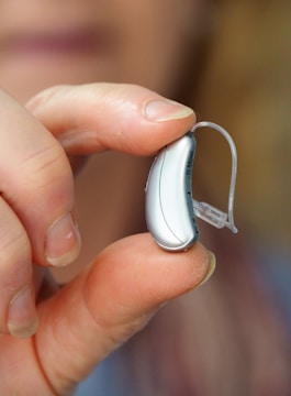 A display of various hearing aid models arranged neatly on a wooden counter.