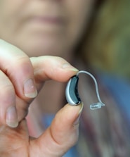 A close-up of a modern hearing aid being adjusted by a professional.