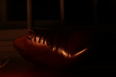 Close-up of hands carefully polishing a leather shoe with a soft cloth.
