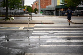A runner jogging through a city street at dawn, with no visible shoe logos.