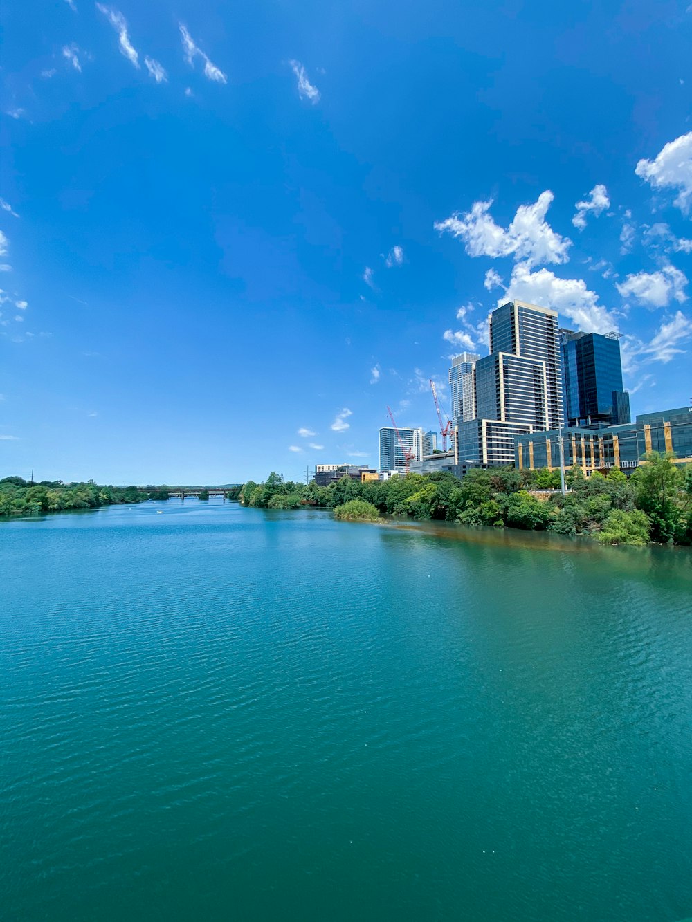 body of water near trees and buildings under blue sky during daytime