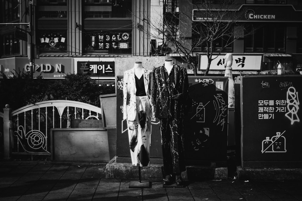 grayscale photo of woman in white dress standing on sidewalk