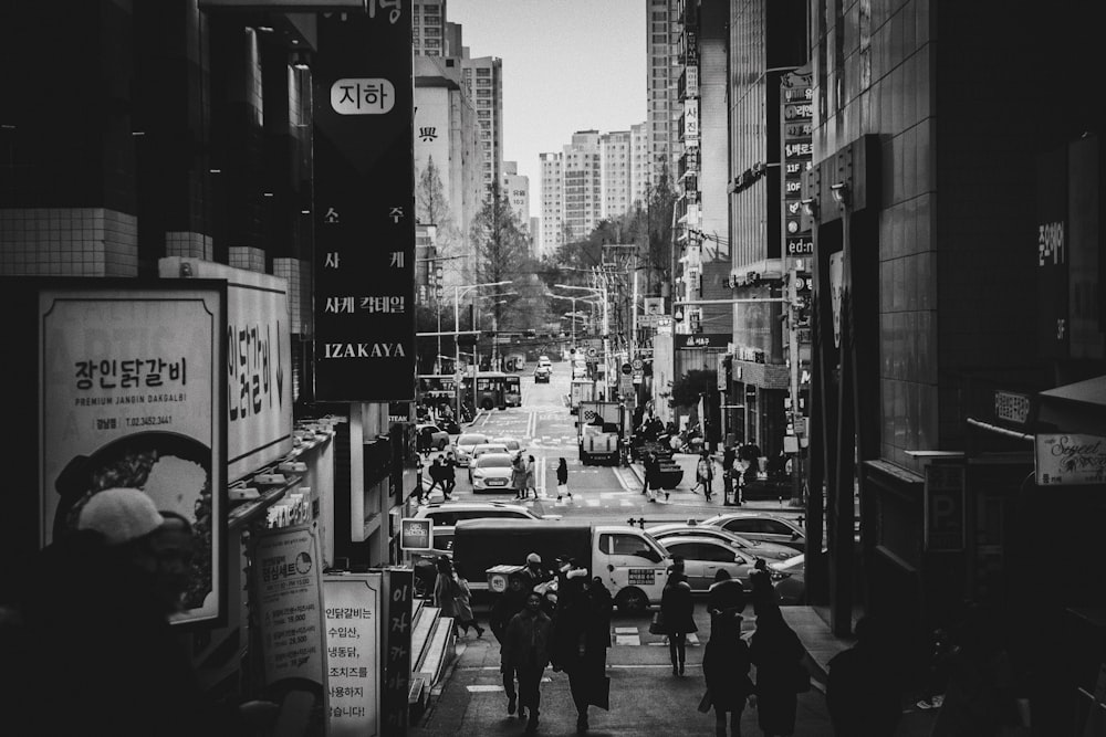 grayscale photo of cars on road between buildings