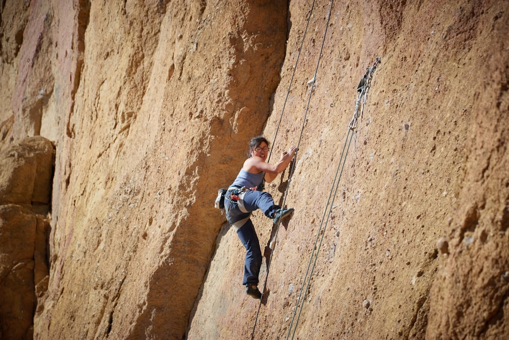 man in blue jacket climbing on brown rock