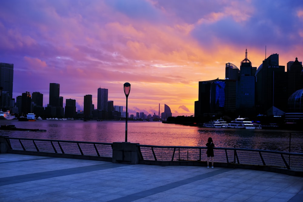 silhouette of person sitting on bench near body of water during sunset