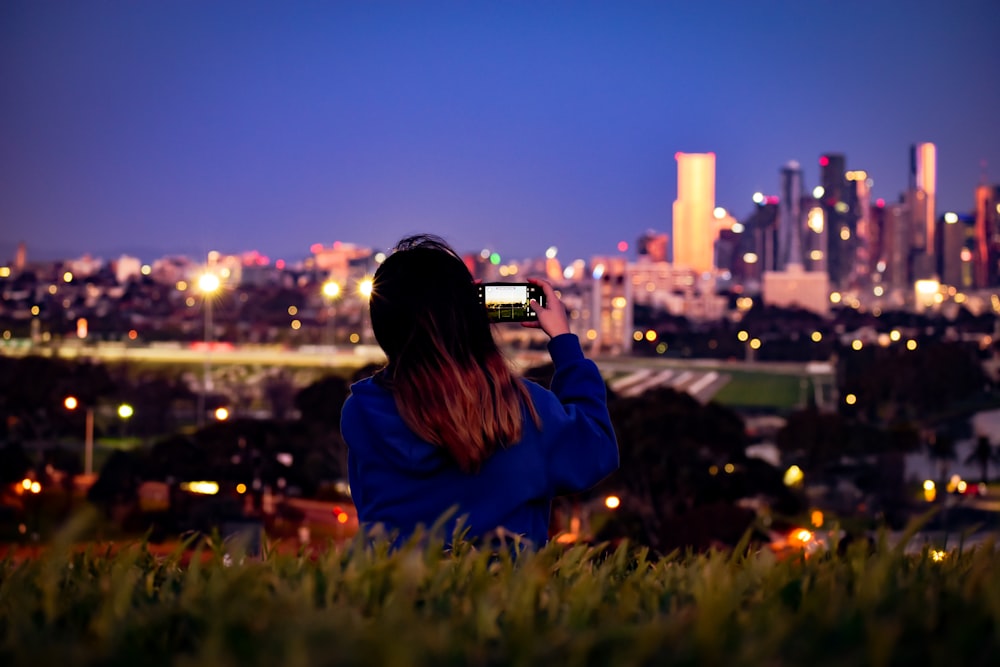 Mujer en chaqueta azul de pie en el campo de hierba verde durante la noche