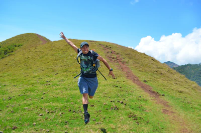 A person joyfully running on a mountain trail, embodying energy and freedom.