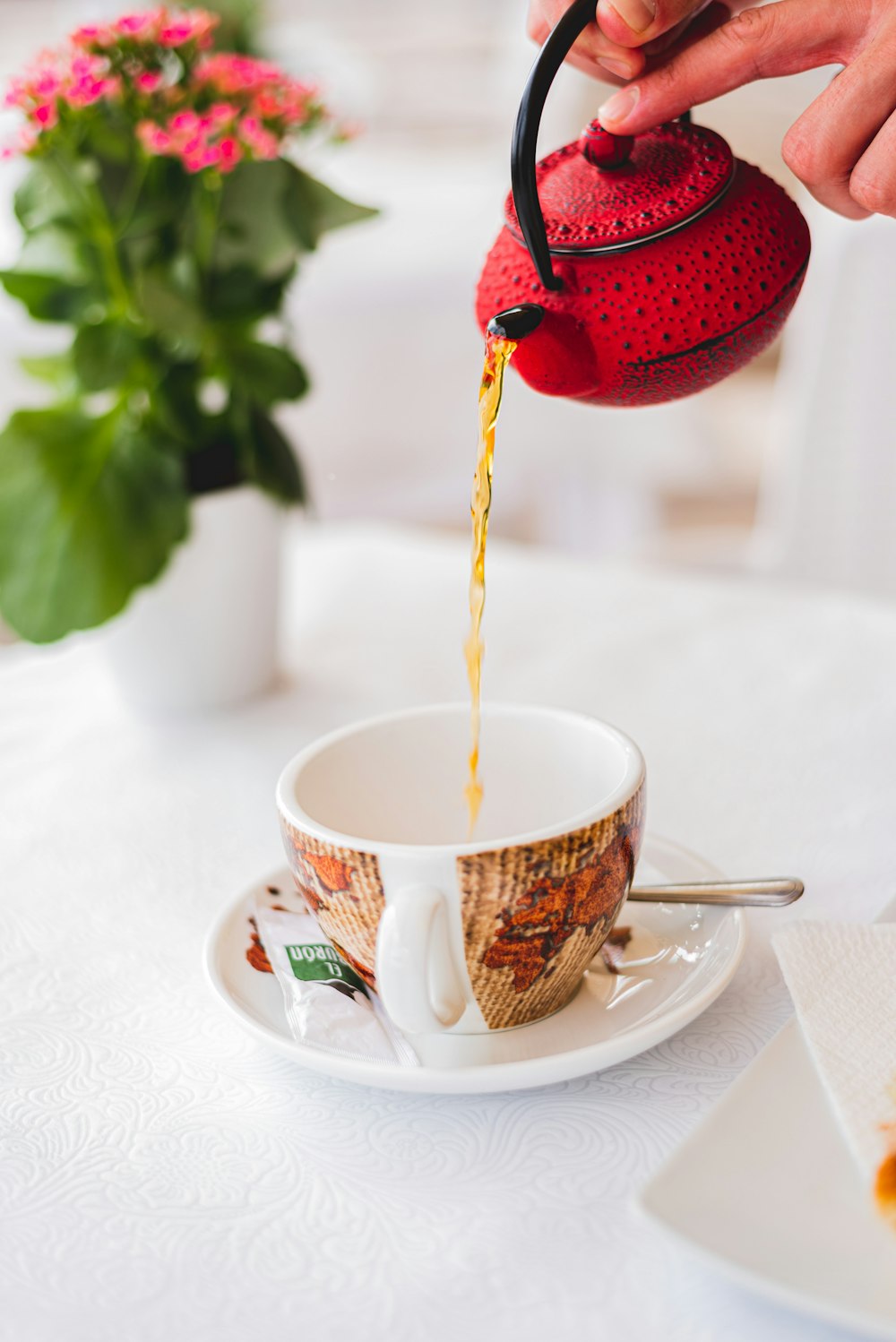 white and red ceramic teacup with red heart shaped ornament on white ceramic saucer