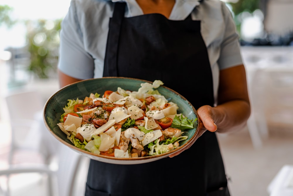 Persona che tiene il piatto di ceramica verde con il cibo