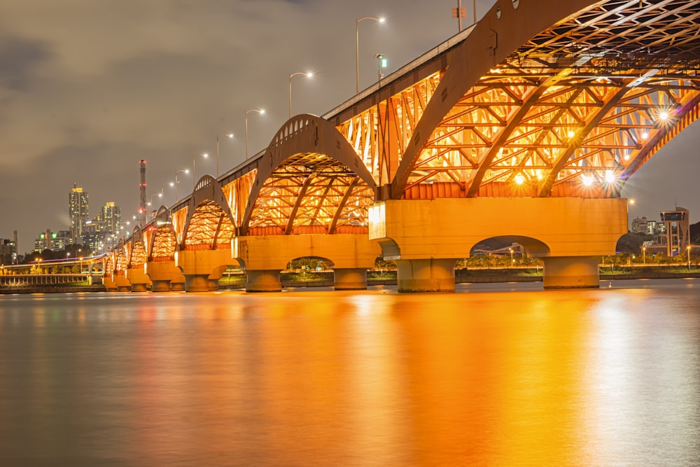 brown and white boat on river under bridge during night time