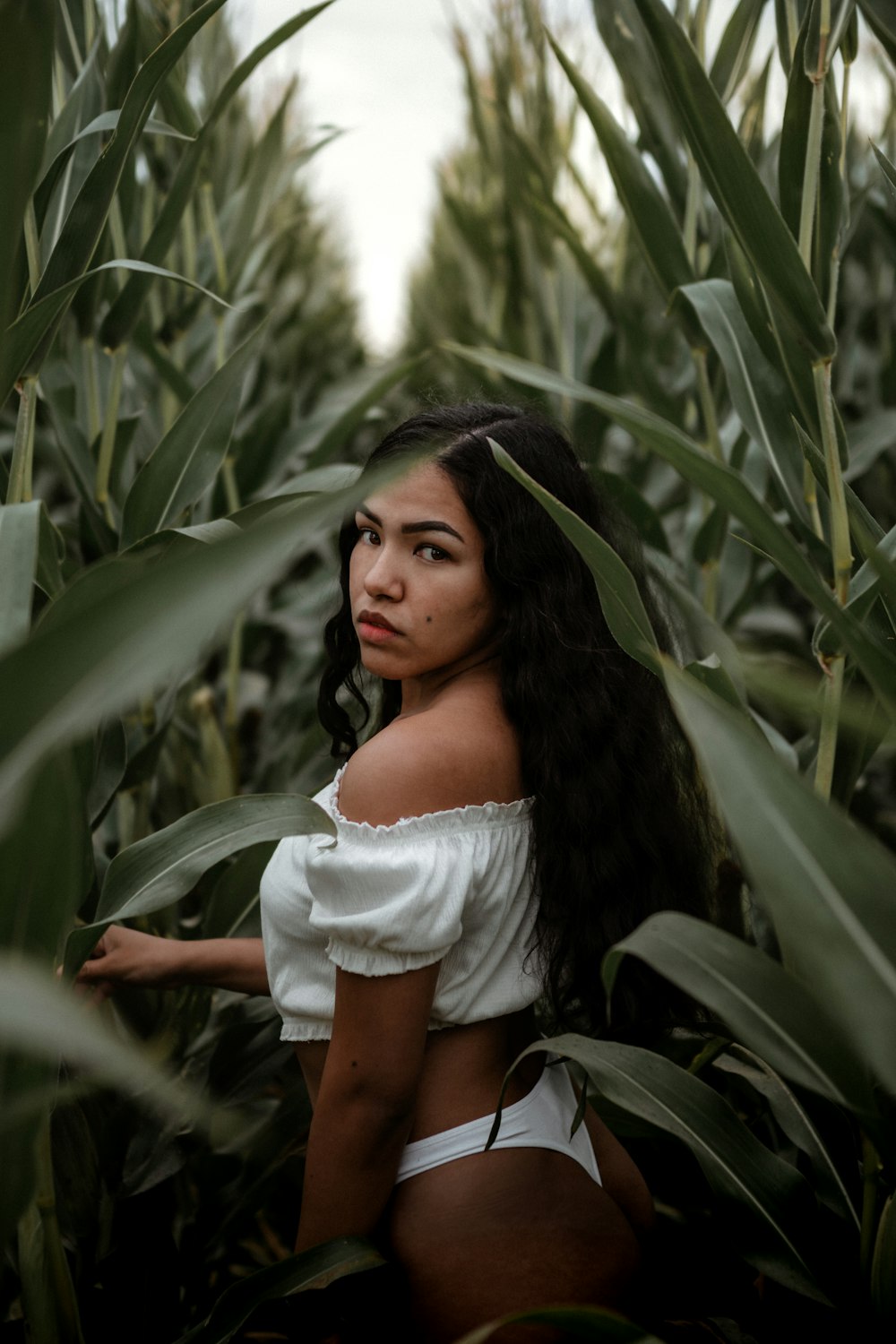 woman in white off shoulder shirt standing near green plants during daytime