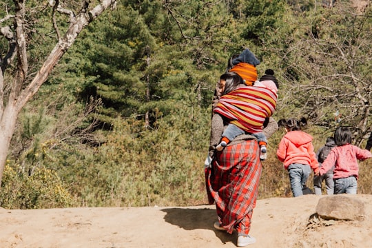 2 person in blue and red striped long sleeve shirt and pants walking on dirt road in Paro Bhutan