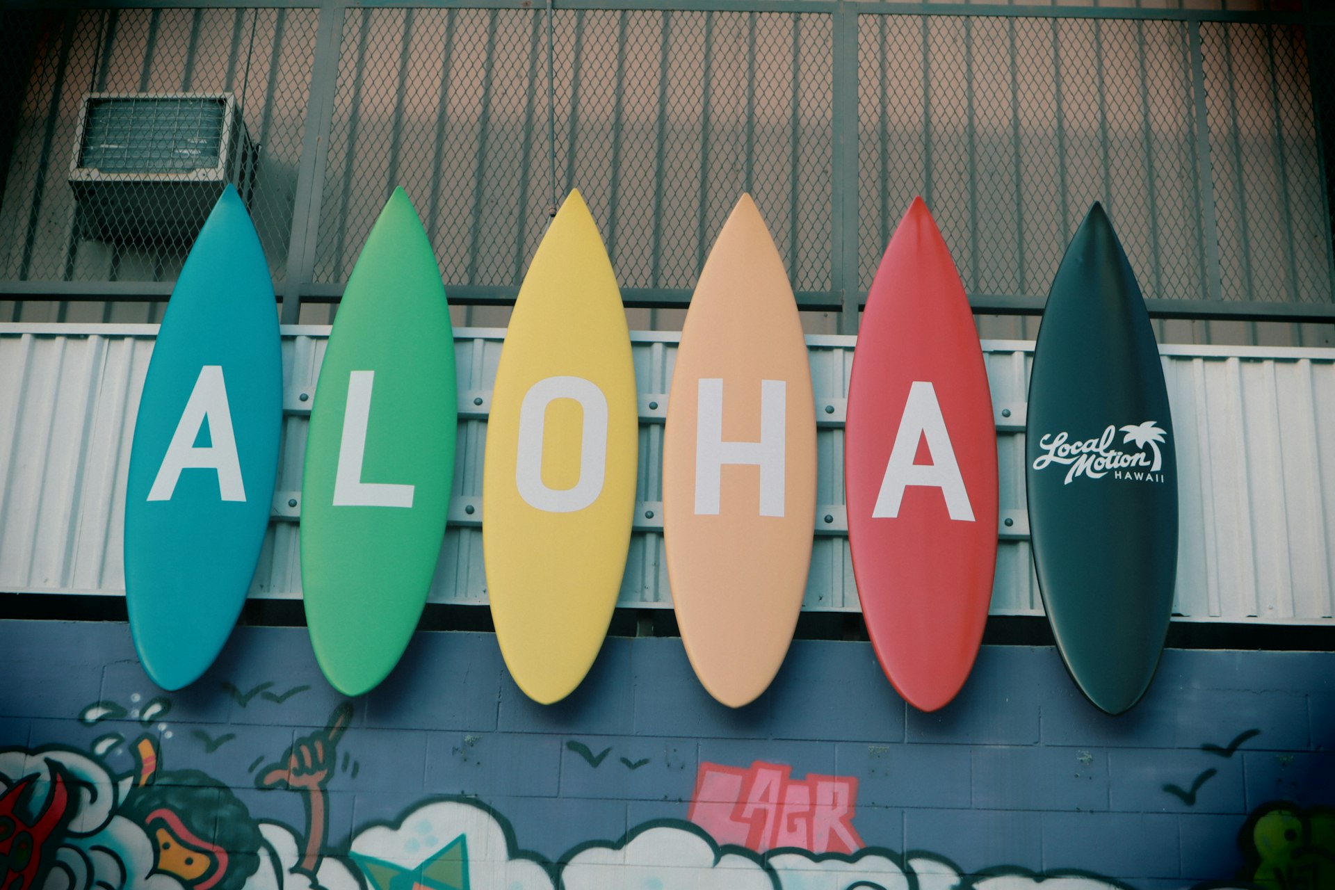 An array of vibrant surfboards neatly lined up, each prominently displaying the word 'Aloha'