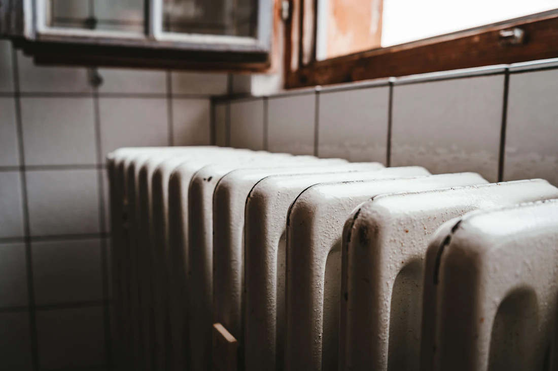 A home radiator beside a wooden window frame