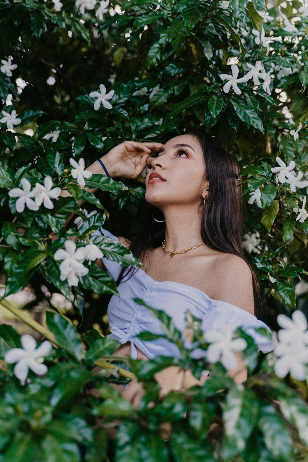 woman in white off shoulder shirt standing beside white flowers