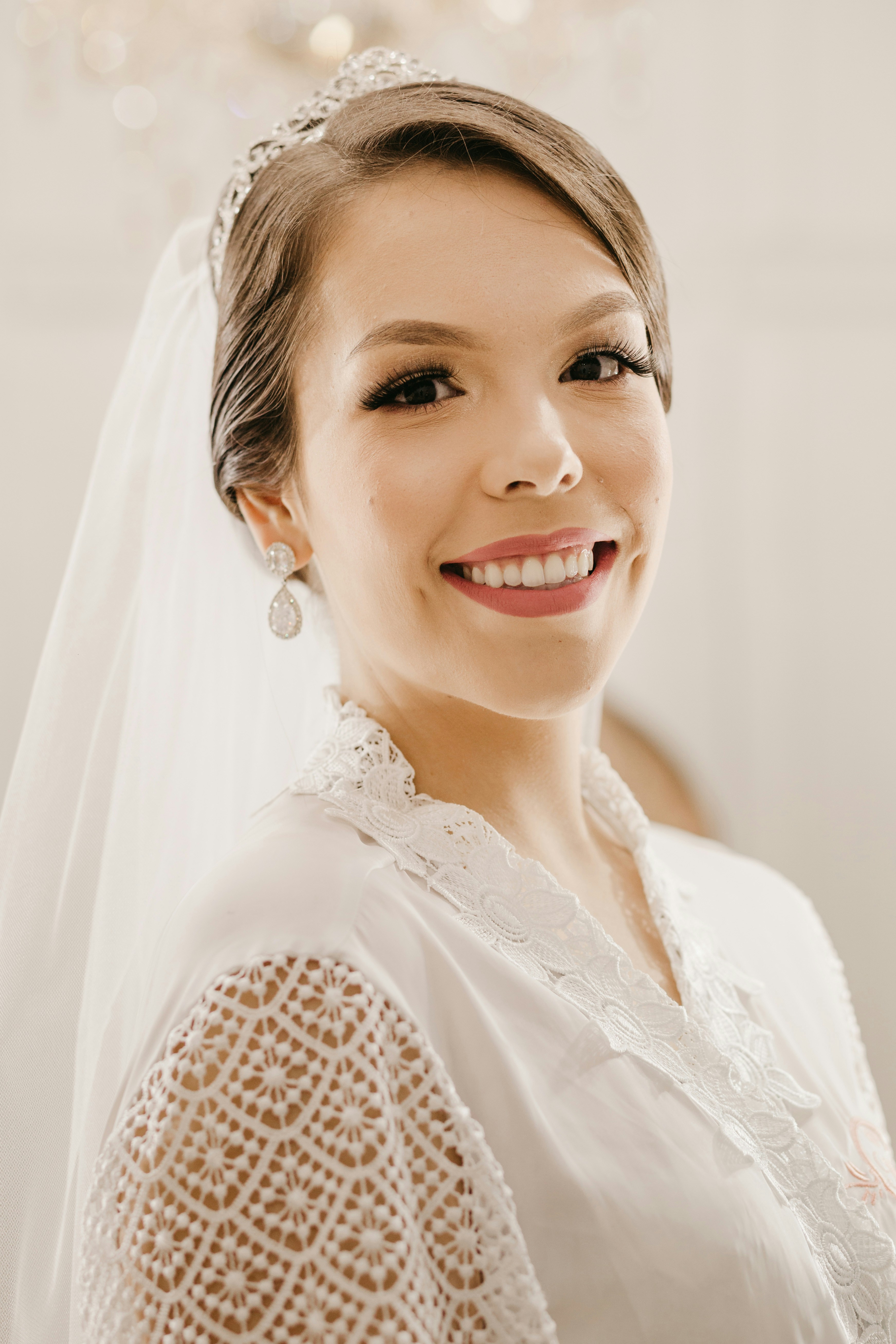Una sposa sorridente con un abito bianco di pizzo e una tiara.