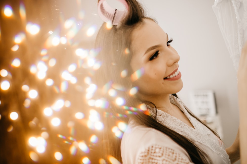 woman in white shirt with yellow string lights on her ears