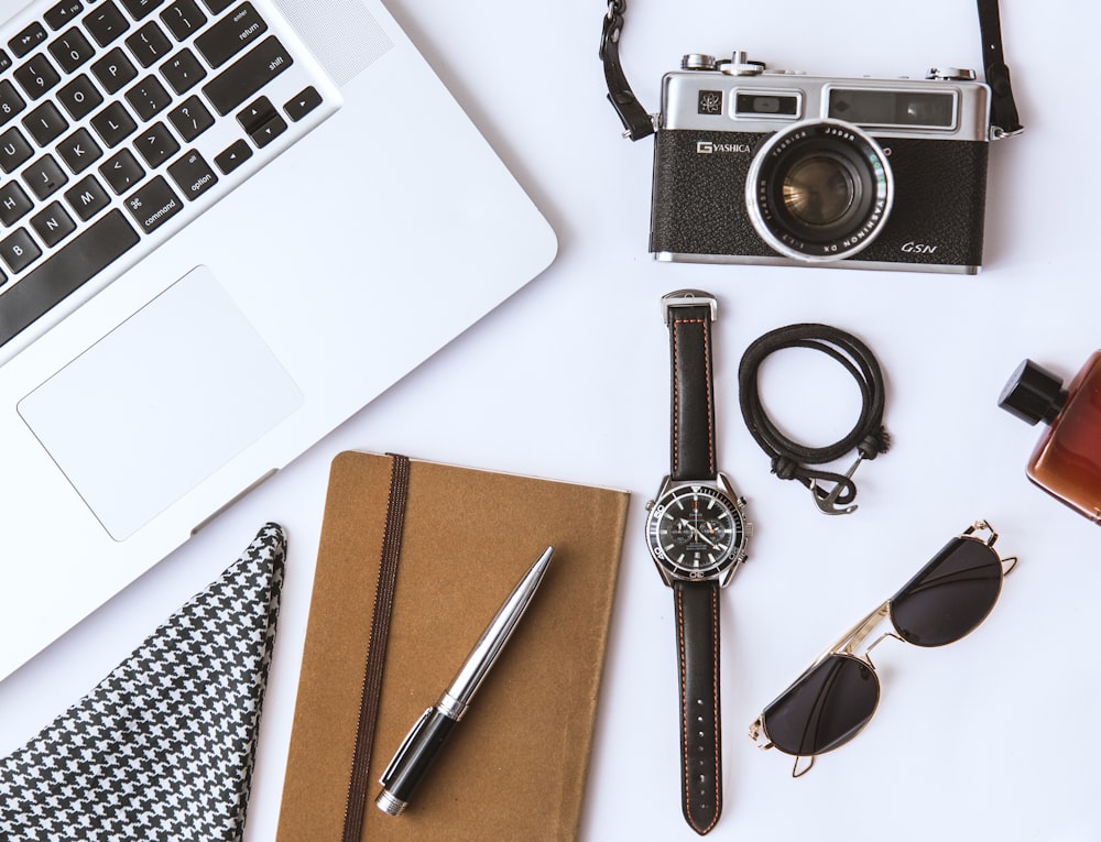 black and silver laptop computer beside black and silver round analog watch