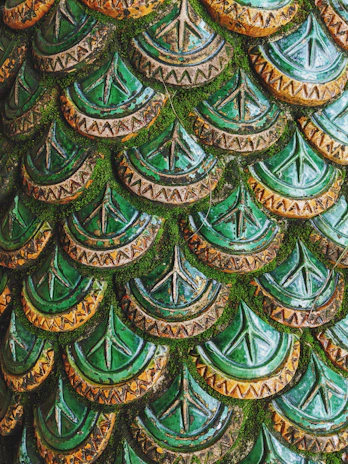 Close-up of intricate zellige tile patterns in rich moss and sage greens on the riad walls.