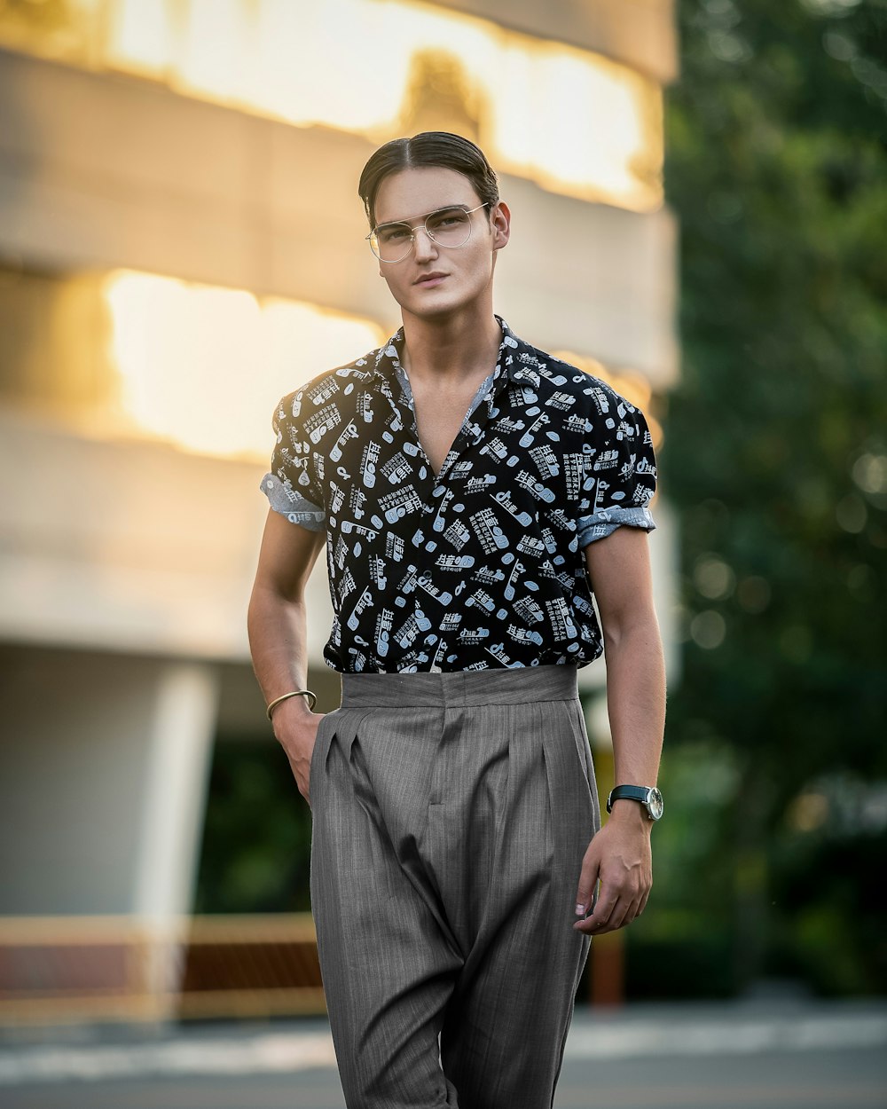 man in black and white floral button up shirt and gray pants wearing black framed eyeglasses