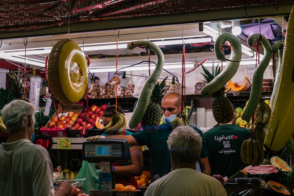 a group of people standing around a fruit stand