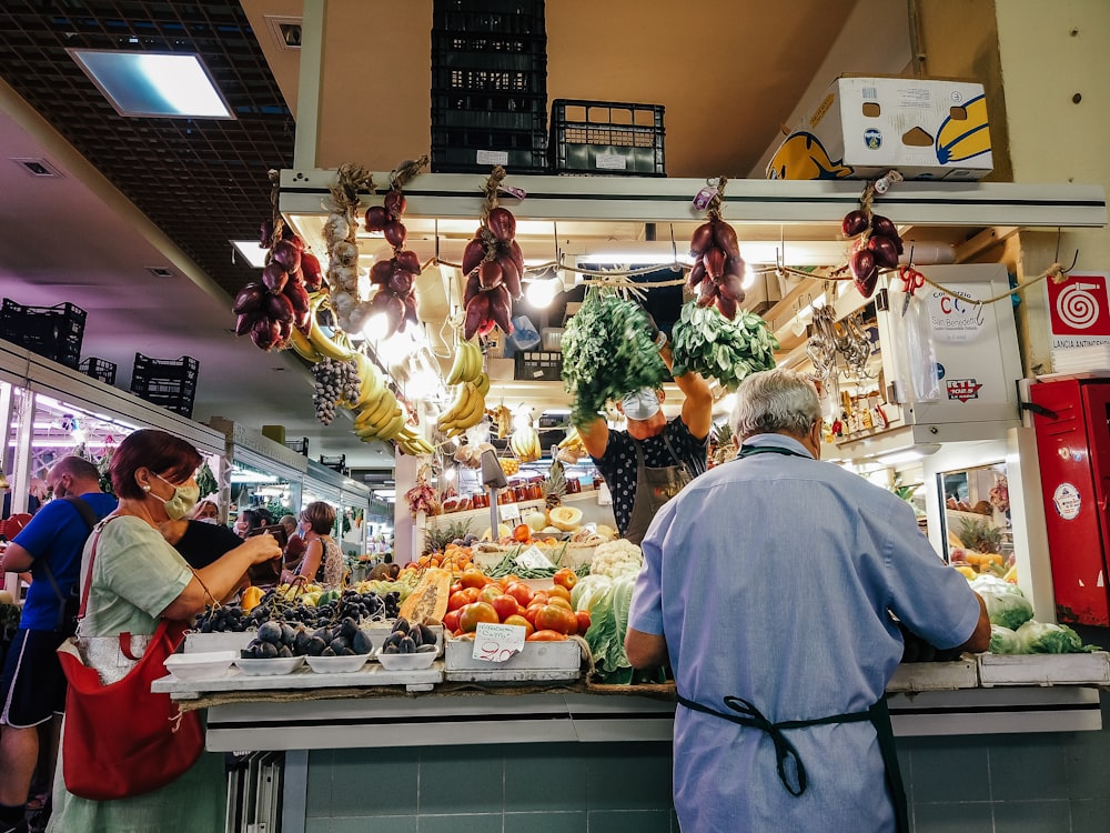 woman in white dress standing in front of vegetable display