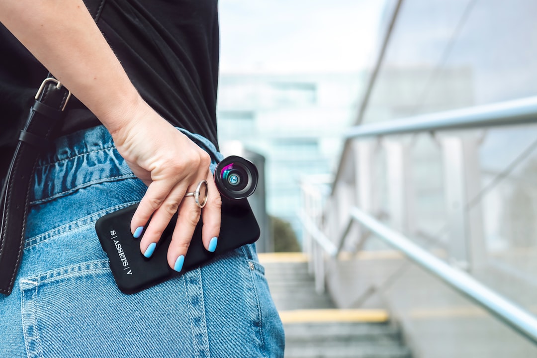 person in black t-shirt and blue denim jeans holding black dslr camera