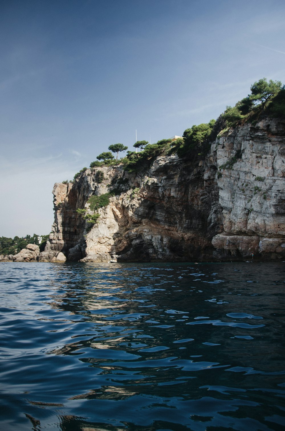 Montaña rocosa marrón junto al mar azul bajo el cielo azul durante el día