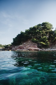 A serene coastal landscape in Antalya with clear blue waters and lush greenery under a bright sky.