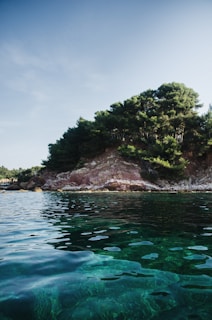 A serene coastal landscape in Antalya with clear blue waters and lush greenery under a bright sky.