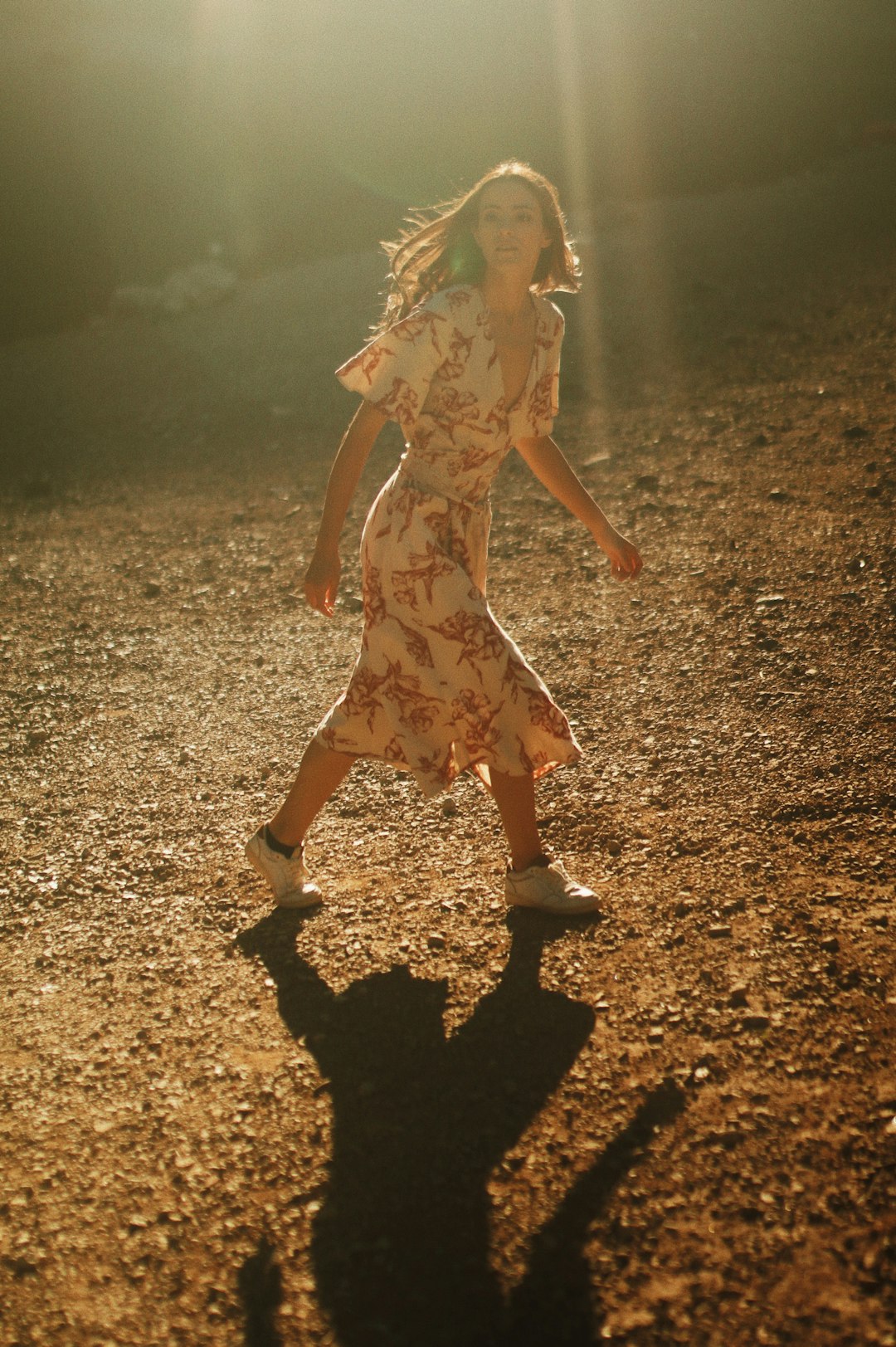 woman in white and red floral dress standing on brown field during daytime