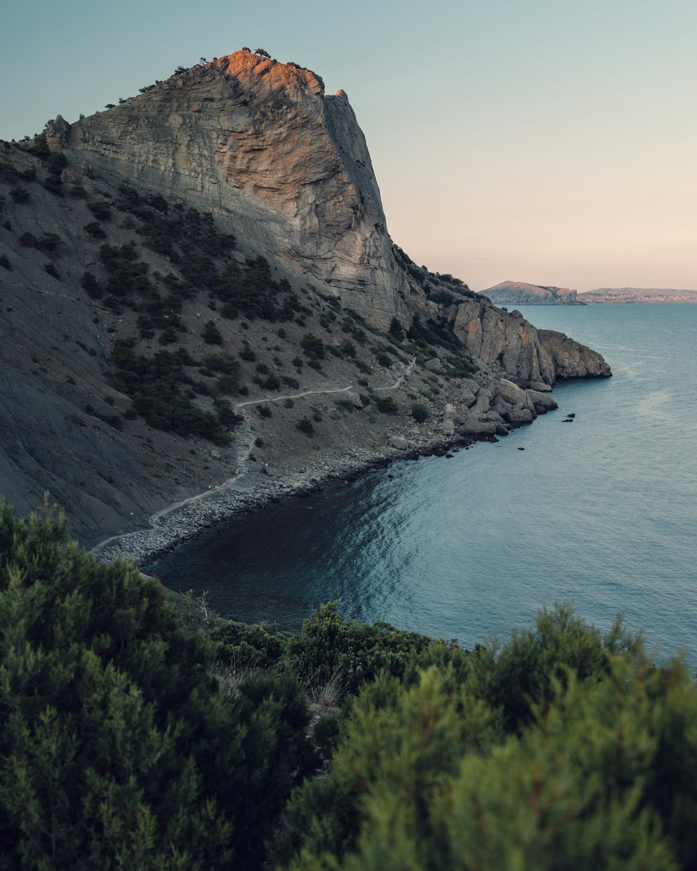 brown rocky mountain beside blue sea under blue sky during daytime